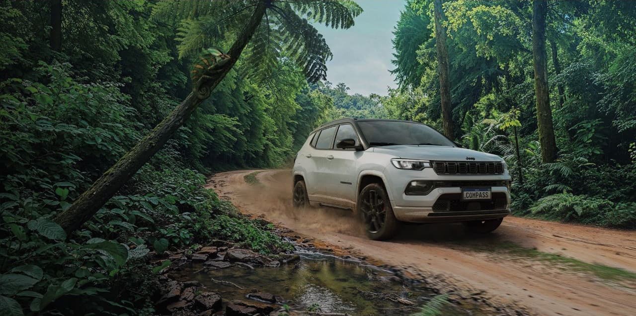 Jeep Compass em estrada cercada por vegetação
